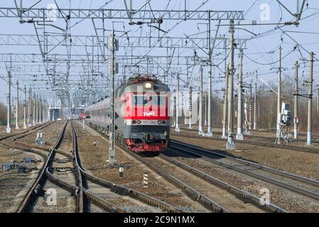 REGIONE DI LENINGRAD, RUSSIA - 05 MARZO 2018: Una locomotiva elettrica a due sezioni della ChS7 con il treno passeggeri sulle rotaie nella primavera del pomeriggio Foto Stock