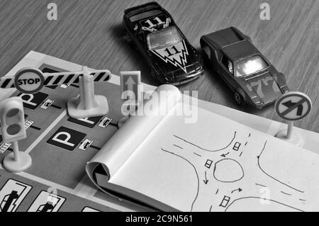 Blocco note, libro delle regole del traffico, Toy Cars, semafori e segno di stop su una scrivania. Studiare e prepararsi per il test di guida Foto Stock