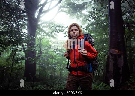 Ritratto di mezza età caucasica donna zaino in spalla, escursioni attraverso la foresta nebbiosa in prima mattina. Foto Stock