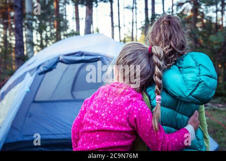 Due ragazzine, che si abbracciano di fronte alla tenda da campeggio. Foto Stock