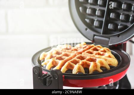 Il processo di preparazione di waffle fatti in casa. Waffle appena sfornati in un ferro da stiro a base di waffle. Messa a fuoco selettiva Foto Stock