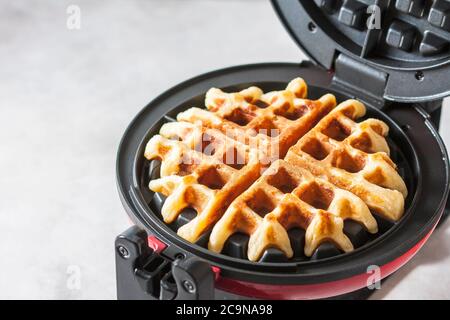 Il processo di preparazione di waffle fatti in casa. Waffle appena sfornati in un ferro da stiro a base di waffle. Messa a fuoco selettiva Foto Stock