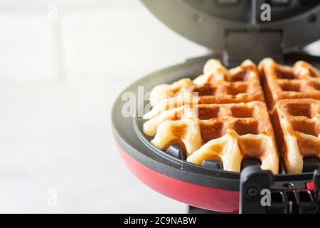 Il processo di preparazione di waffle fatti in casa. Waffle appena sfornati in un ferro da stiro a base di waffle. Messa a fuoco selettiva Foto Stock