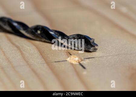 Un ritratto closeup di una tavola di legno con un foro trapanato in essa sull'intersezione di un segno a matita con la punta di foratura del legno che si trova accanto ad essa. Foto Stock