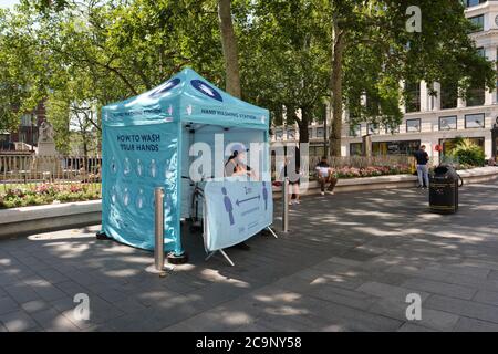Stazione di lavaggio a mano a Leicester Square a Londra, Regno Unito, per fornire maschere, guanti e disinfettante a mani gratuite al pubblico in mezzo alla pandemia COVID-19. Foto Stock