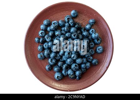 Bacche nere fresche o mirtilli in una piastra di ceramica di argilla marrone fotografata dall'alto. Primo piano di fragole fresche e salutari. Foto Stock