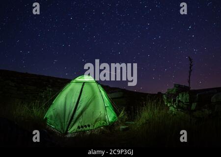 Campeggio tenda vicino alla montagna Dinara -punto più alto della Croazia nelle Alpi Dinariche con luce all'interno è sulla valle di montagna sotto cielo stellato di notte Foto Stock