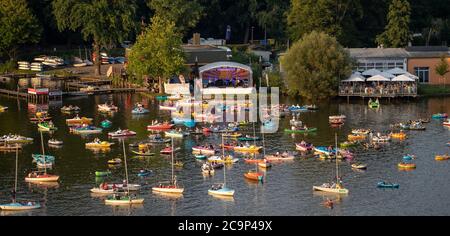 01 agosto 2020, Baviera, Norimberga: La Staatsphilharmonie (h, M) suona sul palcoscenico del lago sul Großer Dutzendteich di fronte agli spettatori che seguono il concerto sulle proprie barche. A causa degli eventi musicali Bardentreffen, Klassik Open Air e Stars a Luitpoldhain, che sono stati cancellati a causa di Corona, l'ufficio di progetto nella Divisione Cultura della Città di Norimberga ha organizzato tre diversi concerti con un week-end di concerti all'aperto sulle rive del Dutzendteich. L'offerta unica intende essere un aiuto e un esperimento di ponte in uno. Il pubblico dovrà portare la loro o Foto Stock