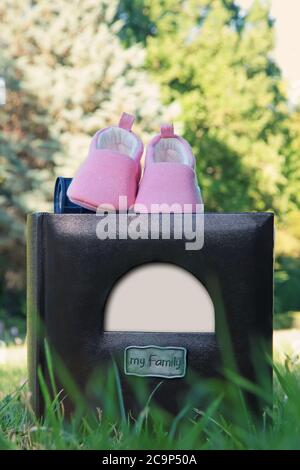 Primo piano album fotografico di famiglia con cornice bianca vuota come spazio vuoto per foto o testo. Bella composizione con un paio di scarpe per bambini neonati su un pho Foto Stock