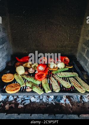 Verdure alla griglia. Zucchine, funghi e zucca su una griglia di metallo su carboni rossi. Foto Stock