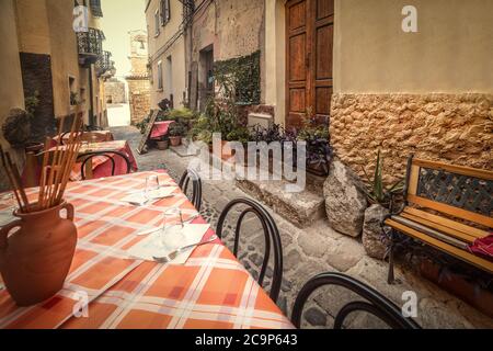 Tavoli e sedie in un vicolo stretto nel centro storico di Castelsardo. Sardegna, Italia Foto Stock