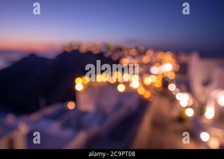 Concetto di giornata mondiale dell'ambiente: Luce bokeh e sfocatura del tramonto crepuscolo città su Santorini, Grecia. Vista mare e paesaggio isolano, paesaggio urbano astratto Foto Stock