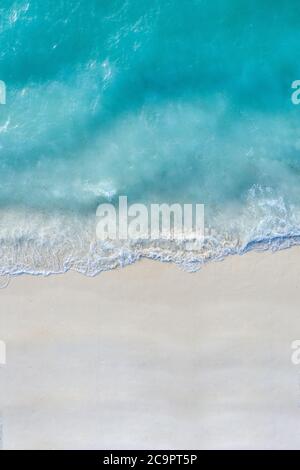 Vista aerea della spiaggia di sabbia e dell'oceano con le onde. Bella spiaggia bianca tropicale vuota e onde di mare visto dall'alto. Bellissima spiaggia di paesaggio marino Foto Stock