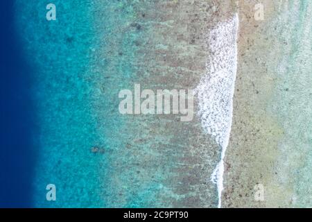 Vista dall'alto foto aerea dal drone volante. Bellissima spiaggia. Vista aerea delle onde calme, che si infrangono alla barriera corallina. Spiaggia oceanica esotica, paesaggio tropicale Foto Stock