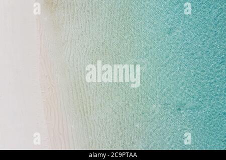 Vista aerea della spiaggia di sabbia e dell'oceano con le onde. Stagione estiva dall'aria. Vista dall'alto dal drone. Concetto di viaggio, spiaggia e onde dalla vista superiore. Foto Stock