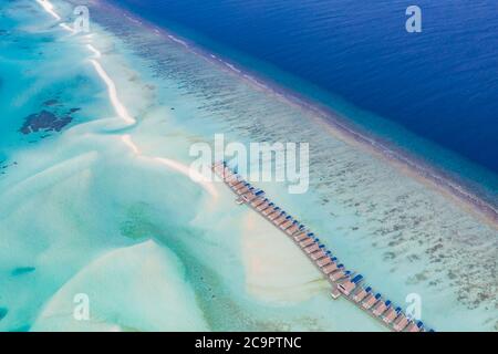 Island resort nell'oceano Indiano, Maldive. Bungalow Luxury Over Water Villas con banco di sabbia e splendida laguna vicino alla barriera corallina dell'oceano Foto Stock