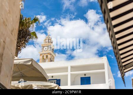 Fira città nella torre dell'orologio di Santorini con architettura bianca. Idilliaca vista esterna della città dalla strada Foto Stock