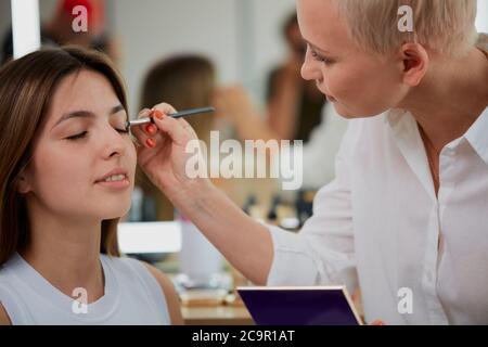 professionista make-up artista, visagiste applicando trucco sugli occhi al master class nella scuola di bellezza Foto Stock