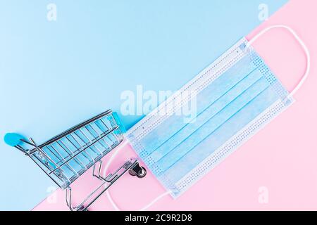Carrello con maschera medica protettiva. Shopping sicuro nel supermercato. Concetto di quarantena. Spazio di copia Foto Stock