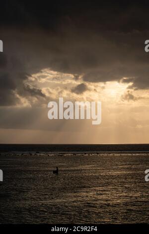 I raggi del sole sul mare scoppiano dalla nuvola. Tramonto spettacolare sul mare, bella scena tranquilla, raggi di luce brillano in acqua, fascio di sole in cl Foto Stock