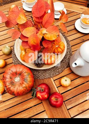 Dall'alto della composizione autunnale di raccolta fresca disposta su tavola di legno con teiera e tazze con bevanda calda Foto Stock