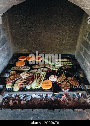 Verdure alla griglia. Zucchine, funghi e zucca su una griglia di metallo su carboni rossi. Foto Stock