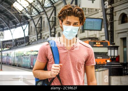 Giovane uomo che lascia la stazione ferroviaria con maschera facciale attivata. Scatto medio. Foto Stock