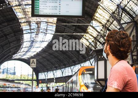Giovane uomo che controlla gli orari della stazione ferroviaria. Vista panoramica. Viaggiare in modo sicuro per i tempi brevi. Chiudi vista Foto Stock