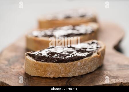 Ciabatta rustica con crema di cioccolato biologica su tavola di ulivo Foto Stock