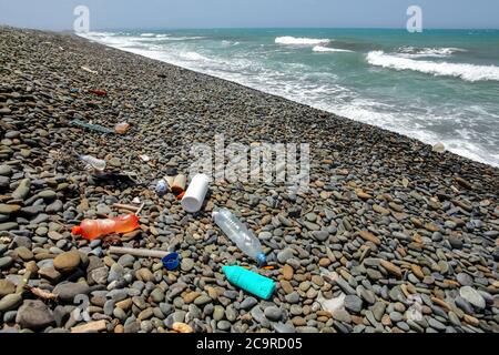 Le bottiglie di plastica spazzano sulla spiaggia di ciottoli selvatici. Concetto di littering oceanico e marino Foto Stock