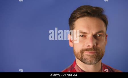 Colpo di testa di un giovane uomo fidato e bearded isolato su sfondo blu con spazio di copia. Foto di alta qualità Foto Stock