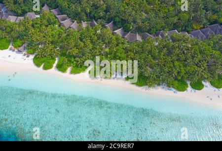 Piccola isola nelle Maldive coperta da palme e circondata da acque turchesi blu con bellissimi coralli e animali, perfetta fuga dal Foto Stock