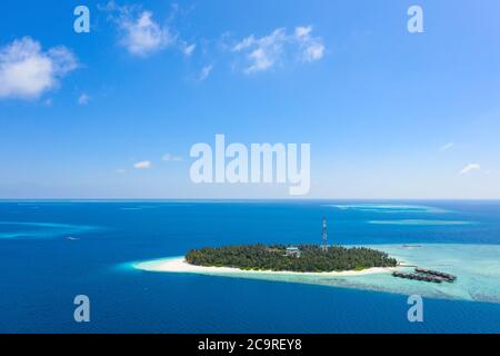 Piccola isola nelle Maldive coperta da palme e circondata da acque turchesi blu con bellissimi coralli e animali, perfetta fuga dal Foto Stock