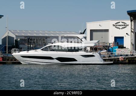 Cantiere Sunseeker a Poole, Dorset UK con yacht in acqua e logo sulla costruzione in background Foto Stock