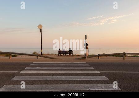 Tre uomini da dietro seduti su una conversazione in panchina mentre si guarda fuori per vedere Foto Stock