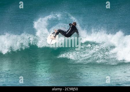 Azione spettacolare come un surfista si svanisce mentre cavalca un'onda a Fistral a Newquay in Cornovaglia. Foto Stock