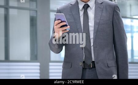 Uomo d'affari in cravatta e vestito che tiene un cellulare in mano. Spazio di copia. Foto Stock