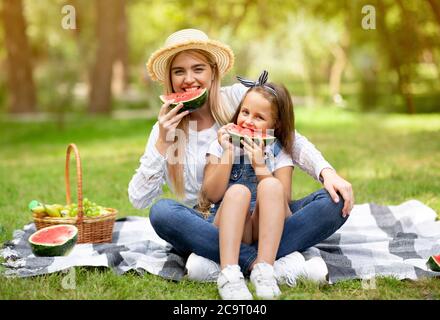 Madre e figlia mangiano frutta durante il weekend di picnic all'aperto Foto Stock