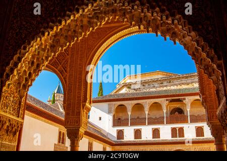 Granada, Spagna 07/13/2010: Vista del famoso Palazzo dell'Alhambra attraverso un cancello con motivi islamici decorativi scolpiti sulla pietra. Vista di un palazzo buil Foto Stock