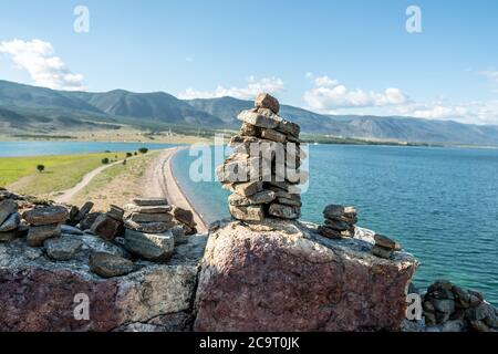 Pila di pietre costruite in cairn sullo sfondo del lago Baikal. Concetto di calma e distacco con la natura Foto Stock