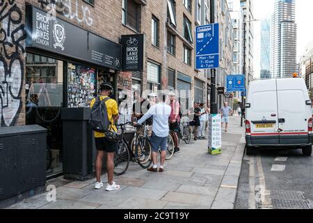Londra - Bethnal Green - 2 agosto 2020 - le persone si accodano all'esterno di un negozio di riparazione biciclette a seguito dell'introduzione del programma di riparazione del ciclo del governo britannico Foto Stock