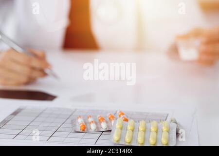 Donna-medico sconosciuto riempie in su la forma di prescrizione in stanza soleggiata, primo piano Foto Stock