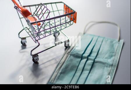 Mascherina chirurgica e carrello di shopping o carrello di shopping a. Illustrare la caduta economica di Coronavirus COVID-19 Foto Stock