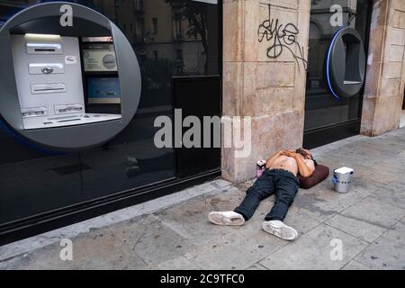 Barcellona, Spagna. 02 agosto 2020. Un senzatetto è visto dormire di fronte agli sportelli automatici di una banca. La mancanza di turismo e le previsioni economiche negative con il crollo del PIL spagnolo a causa della crisi economica derivata dal Covid-19 prendono il loro tributo alle imprese a Barcellona, la chiusura dell'attività commerciale e l'abbandono dei locali. Credit: SOPA Images Limited/Alamy Live News Foto Stock