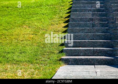 Scale in pietra e prato, primo piano. Gradini grigi e erba nel parco, frammento. Foto Stock
