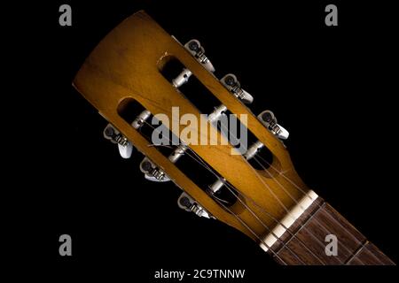 Dettaglio isolato della testa della chitarra acustica con tastiera su sfondo scuro Foto Stock