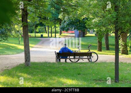 Madrid, Spagna - 31 maggio 2020: Anziano seduto su una panchina accanto alla sua bicicletta in un parco a Madrid. Foto Stock