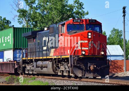 Bartlett, Illinois, Stati Uniti. Un'unica locomotiva Canadian National Railway conduce un treno merci intermodale attraverso una traversata. Foto Stock