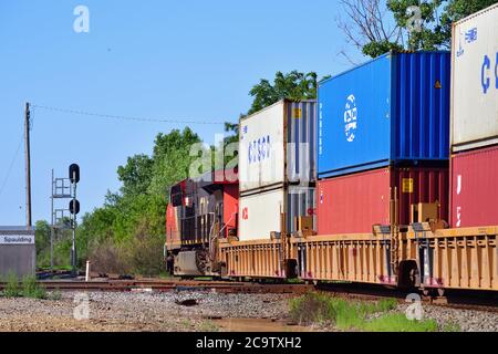 Bartlett, Illinois, Stati Uniti. Un'unica locomotiva ferroviaria nazionale canadese posta alla fine di un treno merci intermodale spinge attraverso un incrocio. Foto Stock