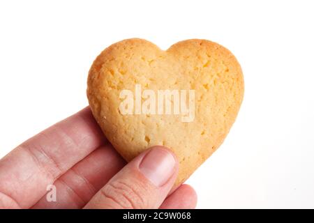 Biscotti a forma di cuore in mano isolati su sfondo bianco. La donna tiene il biscotto a forma di cuore per San Valentino, Natale e altre celebrazioni Foto Stock